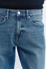Pantalón jean de corte ajustado y tiro medio, en tono azul clásico con efecto deslavado.