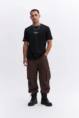 Remera negra de manga corta con cuello redondo y fit regular. Presenta un estampado frontal en blanco con texto minimalista.