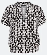 Blusa de viscosa con estampado geométrico en blanco y negro, escote de pico, manga corta y bajo elástico.
