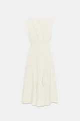 Vestido midi de crepe color blanco marfil, sin mangas, con cuello redondo y corte en la cintura. Falda con vuelo evasé y cierre lateral con cremallera oculta.