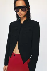 Blazer negro ZW Collection con cuello perkins, manga larga con vuelta en los puños y bajo asimétrico. Presenta detalles de alamares bordados en el frente.