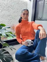 Suéter tejido de punto trenzado color salmón, con cuello alto y mangas largas. Corte ajustado al cuerpo.