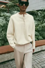 Jersey de punto color marrón, de cuello redondo y manga larga, con cierre frontal parcial de botones.