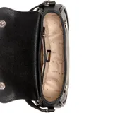 Cartera Guess modelo Danya de formato compacto y estructura rígida, color negro con textura granulada. Presenta solapa frontal con logo triangular metálico de la marca y detalle de correa decorativa con hebilla en la base. Incluye correa larga ajustable para llevar al hombro o cruzada.