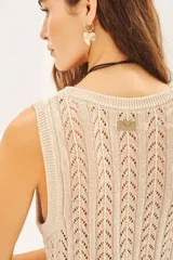 Musculosa sin mangas de tejido punto desagujado en color beige claro, con patrón de rombos calados y brillo sutil por el hilado de lurex y lentejuelas.