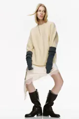 Bota de caña alta confeccionada en cuero color marrón oscuro. Presenta un diseño con punta redonda, taco bajo y suela plana. Incluye detalles de correas con hebillas metálicas en la parte superior de la caña y una tira decorativa tipo espuela con apliques metálicos y detalles grabados en la zona del tobillo.