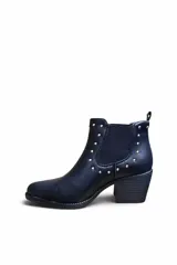 Bota corta de cuero color marrón, con taco cuadrado y elástico lateral. Presenta detalles de tachas metálicas plateadas en el contorno superior y el talón.