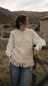 Chaleco de lana natural tejido a mano, con cuello redondo y terminación de flecos en el ruedo. Presenta una silueta relajada y textura rústica.