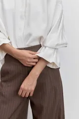 Camisa azul de manga larga con cuello alto fruncido y puños elásticos.