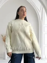 Sweater blanco de tejido de punto con cuello redondo y mangas largas. Presenta un diseño con rombos y flecos.