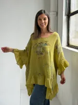 Blusa color verde pistacho, de corte holgado, manga corta con volados y diseño asimétrico con volado en el ruedo. Cuenta con un estampado floral difuminado en el frente.