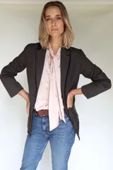 Blazer femenino forrado de corte tradicional, levemente entallado en la cintura, con mini hombreras, botón metálico con escudo y terminación desflecada.