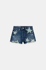 Shorts de denim de tiro medio en color azul, con diseño de estrellas deslavadas, roturas y terminaciones deshilachadas. Cuenta con trabillas, cinco bolsillos y cierre frontal con cremallera y botón metálico.