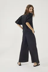 Pantalón culotte negro de lino orgánico, con cintura alta, diseño plisado y bolsillos laterales.
