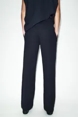 Pantalón de tiro medio confeccionado en tejido de punto elástico con pierna recta. Cuenta con cintura elástica ajustable mediante cordones y bolsillos laterales.