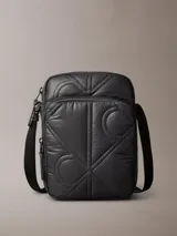 Cartera reporter Calvin Klein color negro, con diseño acolchado y pespuntes que forman el monograma de la marca. Cuenta con compartimento principal con cierre, bolsillo delantero con cremallera y correa ajustable para el hombro.