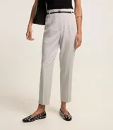 Pantalón zanahoria de vestir color gris claro, con cintura alta, cinturón con hebilla metálica y corte holgado en las caderas que se estrecha en las piernas.