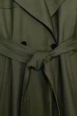 Trench oversize de Zara Woman Collection, color verde militar, con cuello solapa, cierre frontal cruzado con botones y cinturón ajustable del mismo tejido. Presenta mangas largas con trabillas ajustables y bolsillos delanteros.