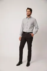Pantalón de vestir marrón oscuro, de corte slim fit, con bolsillos laterales y traseros. Se ajusta a la cintura con cinturón de cuero negro.