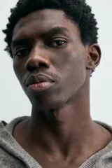 Jersey de lana gris, corte regular, con cuello pico que incorpora una capucha y manga larga. Presenta acabados en rib en puños y bajo.