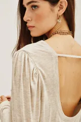 Remera de viscosa en color beige, de manga larga con detalle de frunces en los hombros y un pronunciado escote en la espalda con tira horizontal.