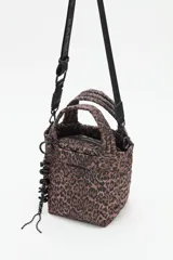 Bolso tipo tote mini acolchado con estampado de leopardo en tonos marrones y negros. Presenta asas cortas acolchadas y una correa larga ajustable con inscripción. Incluye un llavero colgante con letras negras.