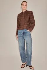 Blazer de cuello subido y manga larga, con diseño peplum en el bajo y cierre frontal con botones. Confeccionado en tejido texturizado a cuadros.