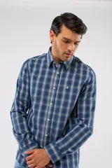 Camisa de manga larga con diseño de cuadros en tonos azules, blancos y negros. Presenta cuello clásico, cierre frontal con botones y logo bordado en el pecho. Corte semi slim.