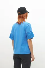 Remera celeste con broderie, de mangas cortas con volados.