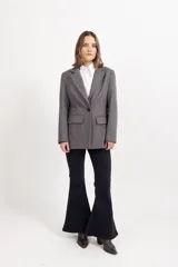 Blazer de paño fantasía en color beige, con solapas clásicas, cierre frontal de botones y dos bolsillos delanteros con solapa. Presenta una estructura entallada con forro interior.