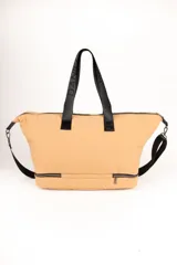 Bolso de gran capacidad color beige, con asas fijas superiores y correa de cinta negra desmontable y regulable. Presenta un bolsillo externo con cierre, un compartimento inferior con cierre y logo de la marca Daniel Cassin en el frente.