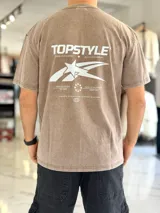 Remera oversize de efecto lavado color marrón, con diseño gráfico estampado en la espalda que incluye texto y una estrella estilizada.