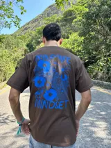Remera marrón con estampa azul de flores y texto "Abundance is a mindset".