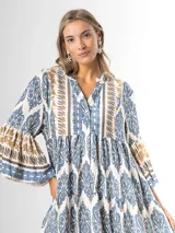 Maxi vestido largo de fibrana en color blanco con estampado paisley y geométrico en tonos azules y tostados, con escote en V, mangas largas amplias y diseño holgado con volados en la falda.