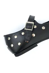 Zapato tipo Mary Jane de cuero negro con tachas plateadas, punta redondeada y tira con hebilla.