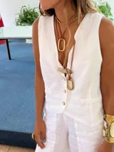 Chaleco de lino color beige, con escote en V, cierre frontal con botones y bolsillos laterales decorativos.