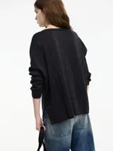 Sweater negro de hilo con textura brillosa, escote en V y manga larga.