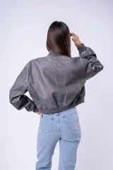 Campera tipo bomber de cuero sintético con efecto desgastado, cuello, puños y ruedo de tejido elástico acanalado, cierre frontal y bolsillos laterales.