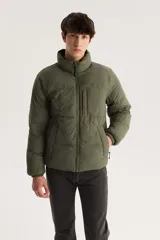 Campera puffer verde militar con cuello alto, cierre frontal con cremallera y bolsillo pequeño en el pecho.