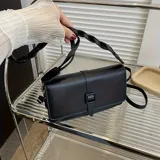 Cartera bandolera rectangular de cuero sintético negro con correa de hombro trenzada y cierre con hebilla.