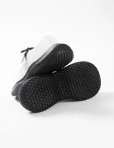 Zapatilla blanca con plataforma, cordones y tirador con broche.