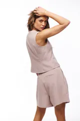 Chaleco color rosa pálido con escote en V y cierre frontal con cuatro botones marrones.