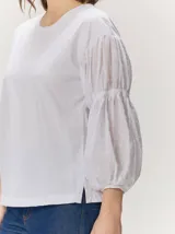 Remera blanca con cuerpo de algodón liso y mangas abullonadas semitransparentes con textura de lunares.