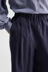 Pantalón azul marino de tiro medio con sutiles rayas verticales blancas, cintura elastizada, perneras amplias y bolsillos tipo ojal.