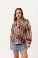 Camisa de gasa estampada traslúcida con diseño geométrico de rombos en tonos lila, naranja y negro. Tiene calce liviano y fluido, abotonado frontal y volado en la cartera.