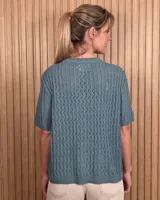 Cardigan de punto color tostado, de manga corta y cuello redondo, con cierre frontal de botones y diseño texturizado.