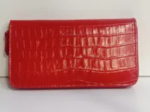 Billetera rectangular con cierre perimetral, confeccionada en cuero con textura de reptil. Cuenta con múltiples compartimentos internos para tarjetas, documentos y billetes, además de un bolsillo interior con cierre para monedas.