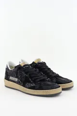 Championes de caña baja Golden Goose modelo Ballstar, color negro con acabado brillante o glitter en los laterales y gamuza en puntera y cordones. Presentan efecto desgastado en la suela de goma color beige.