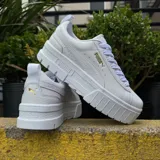 Championes Puma modelo Mayze Classic, color blanco con plataforma alta y detalles en dorado. Presentan diseño de caña baja con cordones y suela de goma con relieve.