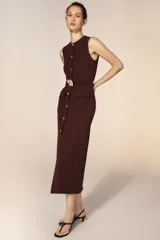 Vestido midi sin mangas de cuello redondo, con cierre frontal de botones dorados y cinturón integrado con hebilla metálica. Presenta bolsillos delanteros con solapa y una abertura en el bajo frontal.